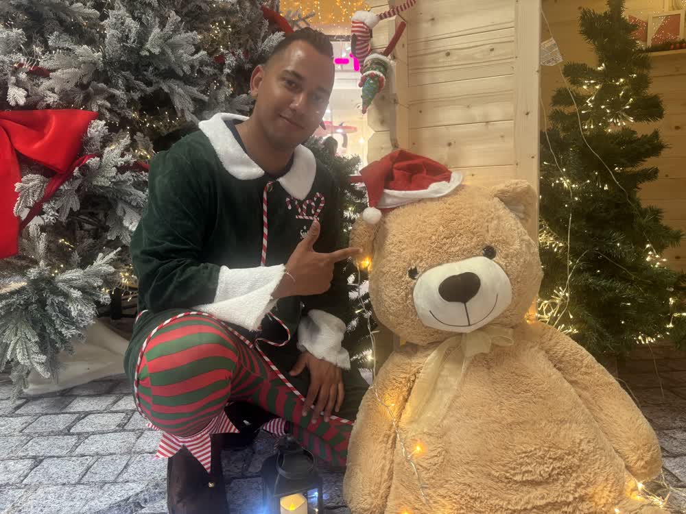 Lutin de Noël posant avec un ours en peluche géant lors d'une animation d'arbre de Noël en entreprise 974