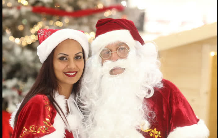 Père Noël et Mère Noël souriants devant le sapin lors d'un événement de Noël à La Réunion